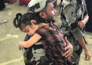 رجل أمن يحمل طفلة خلال قيام والدتها برمي الجمرة الصغرى