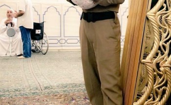 صورة لعسكري يحمل طفلاً بالمسجد النبوي كي يتمكن والده من الصلاة