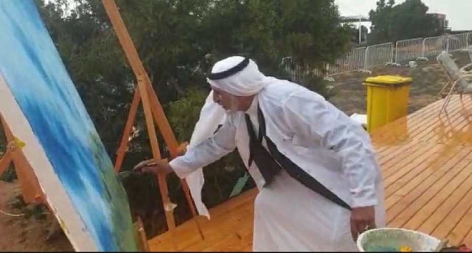بالفيديو.. فنان تشكيلي يواصل الرسم أثناء المطر بموسم السودة