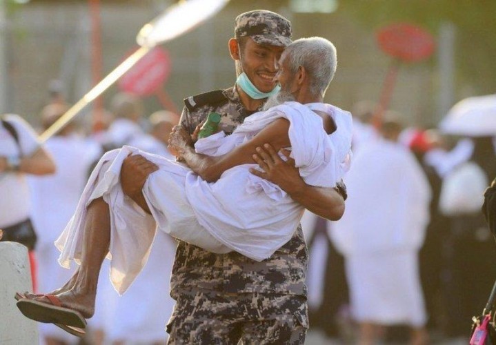 صورة لرجل أمن يبتسم وهو يحمل حاجا نال منه التعب يخطف الأنظار