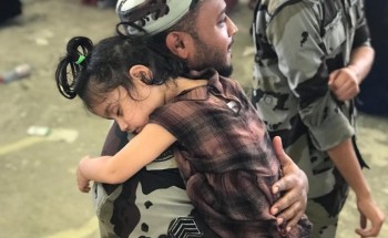 رجل أمن يحمل طفلة خلال قيام والدتها برمي الجمرة الصغرى رجل أمن يحمل طفلة خلال قيام والدتها برمي الجمرة الصغرى